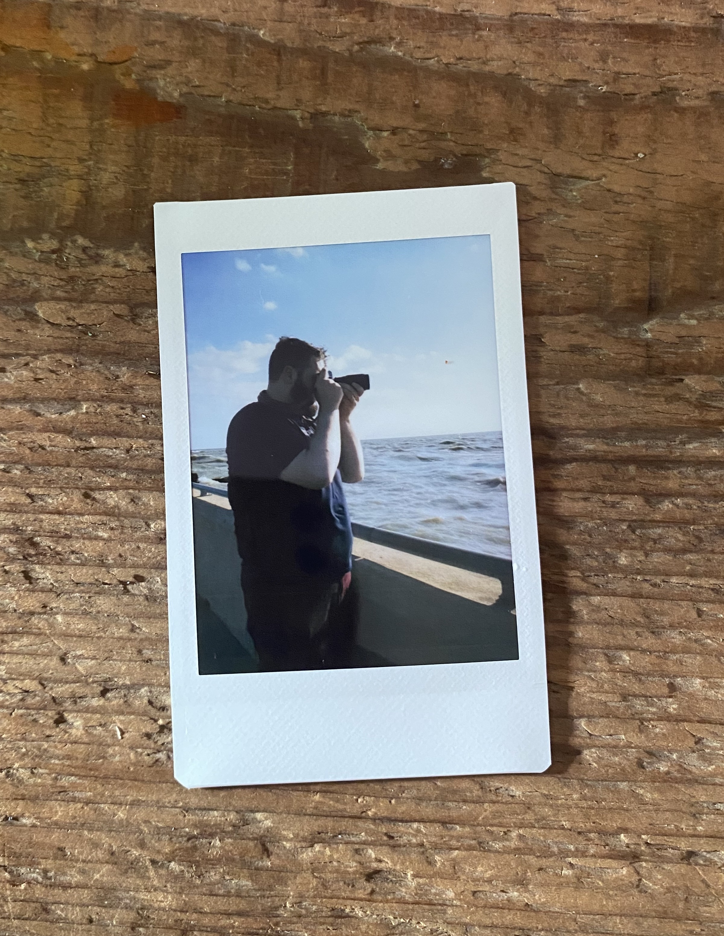 Selfie taken with a film camera in a hand mirror balanced on my knee. Only the top of my head and the camera can be seen.